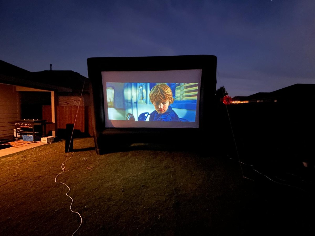 Outdoor movie night with a movie playing on the inflatable screen at dusk
